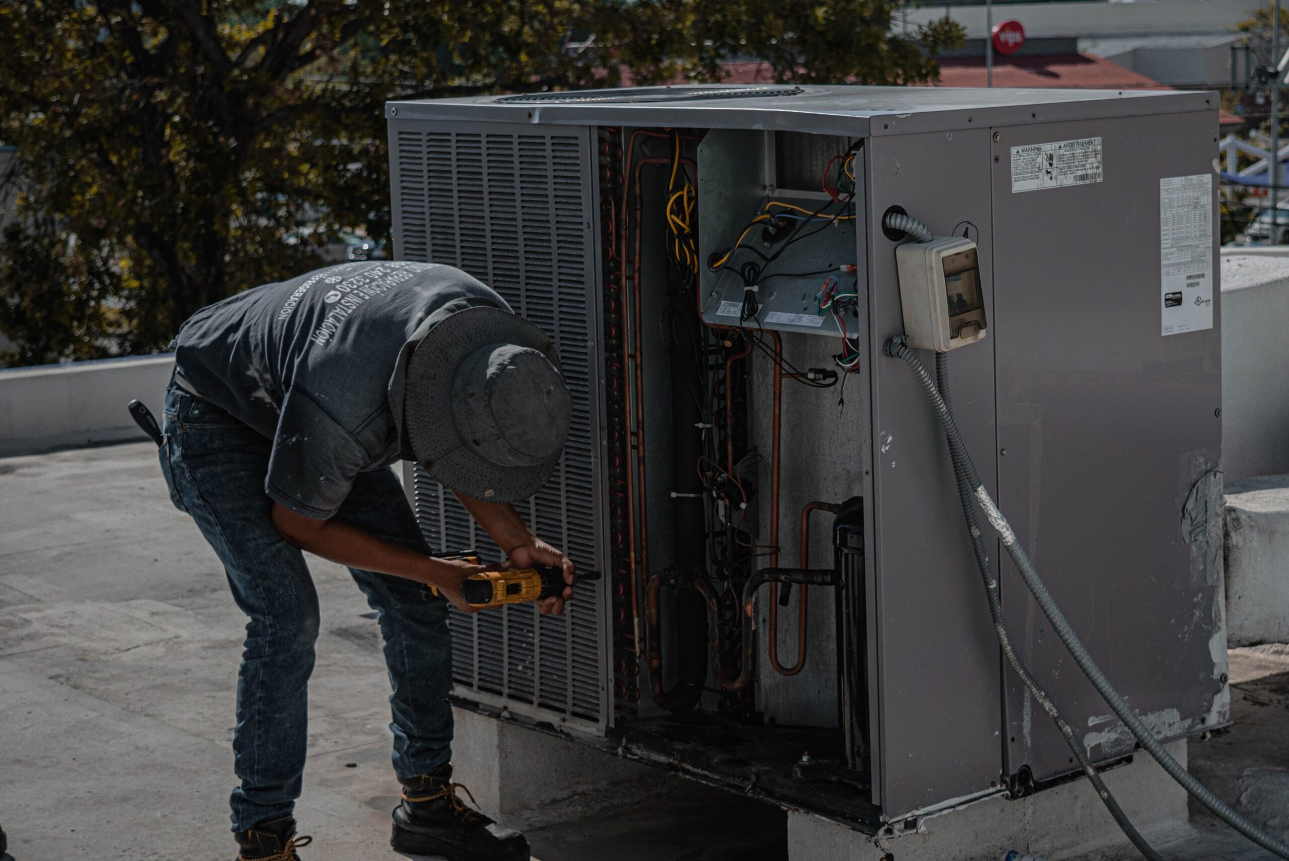 service-1 A technician is repairing an air conditioning unit on a rooftop, demonstrating skilled manual work.